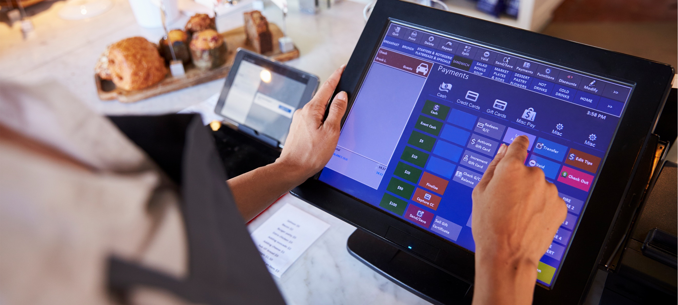 A restaurant employee using a touchscreen point-of-sale terminal